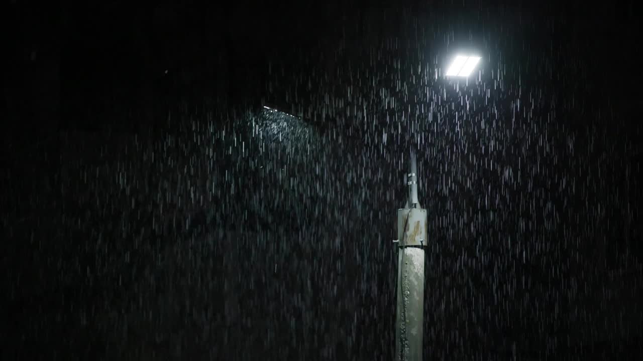 夜间大雨下的双led灯柱。中等尺寸的雨滴对着灯柱明亮的灯光。视频素材