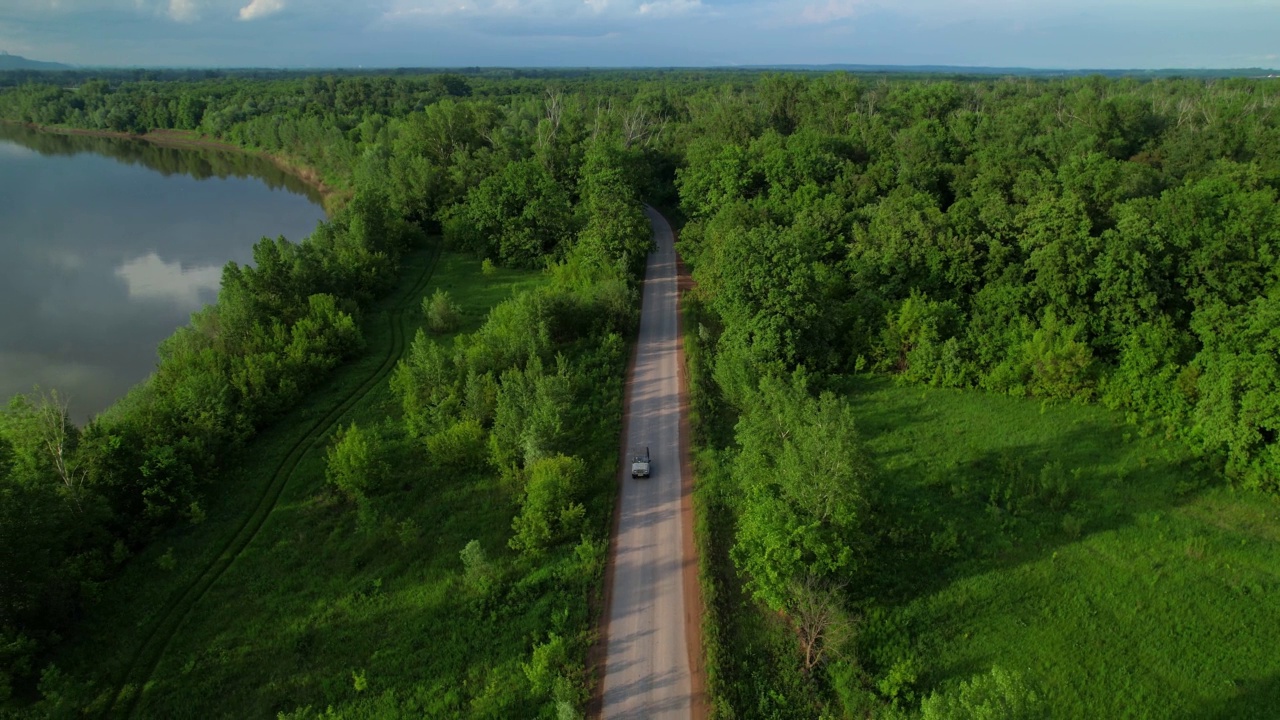 一辆白色汽车正沿着公路驶进森林。视频素材