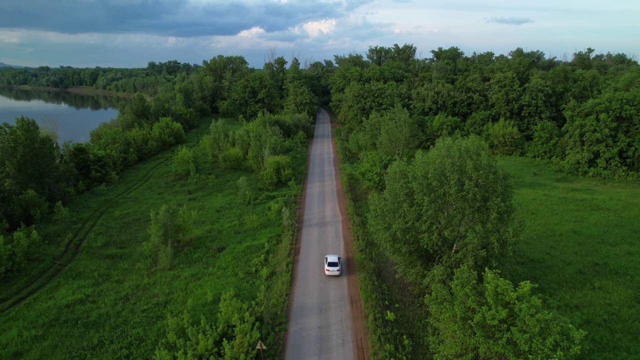 一辆白色汽车正沿着公路驶进森林。视频素材