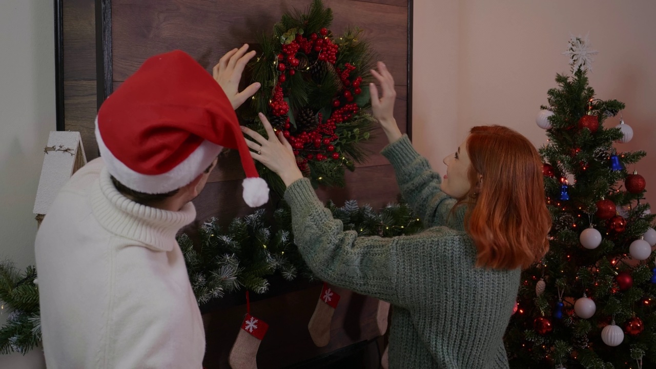一对夫妇正在壁炉上安放圣诞花环视频素材