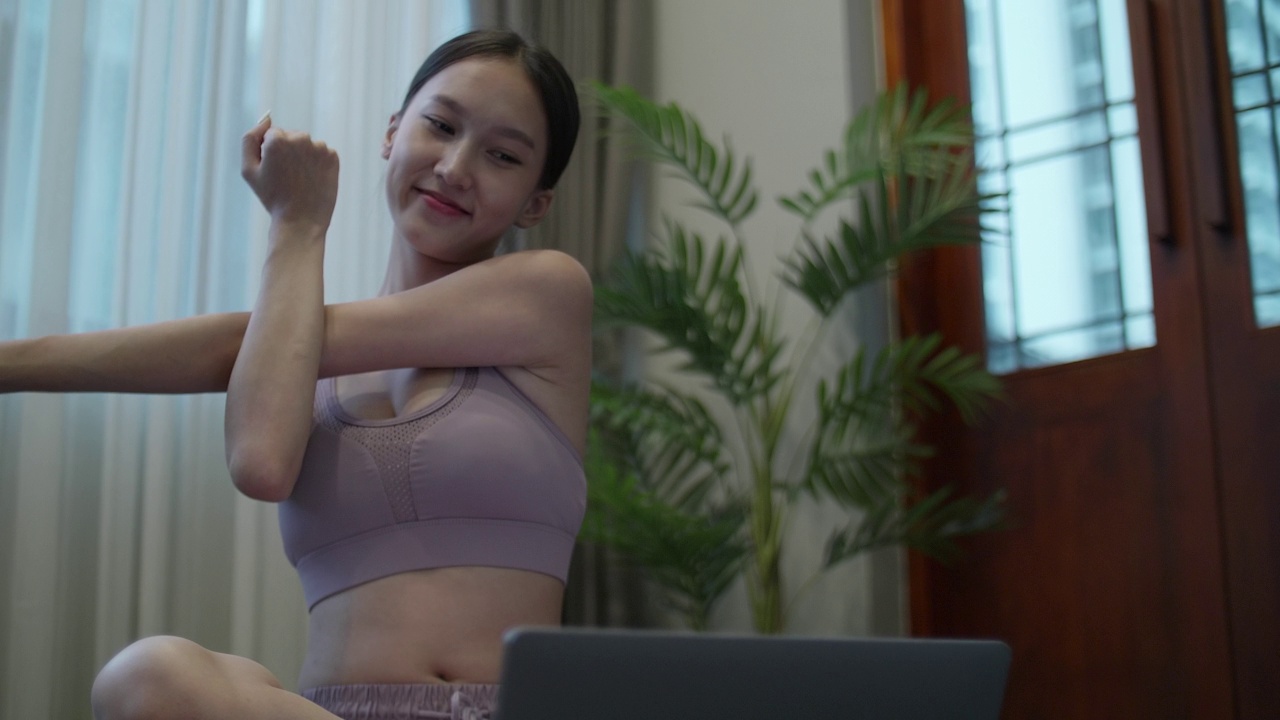 年轻女子在公寓用笔记本电脑看瑜伽教程视频素材