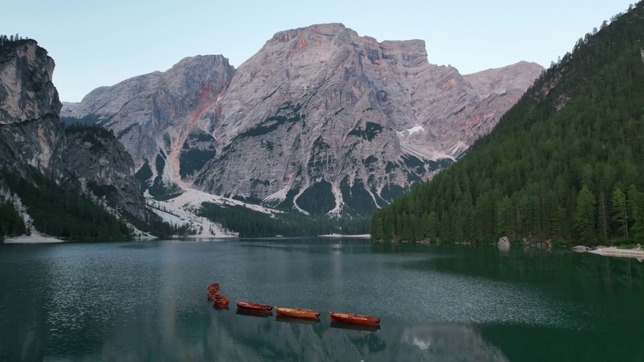 最美丽的布拉斯湖(Lago di Braies)也被称为Pragser Wildsee。白云石山脉,意大利。飞过碧绿平静的水面，小船在一片生涩。视频素材