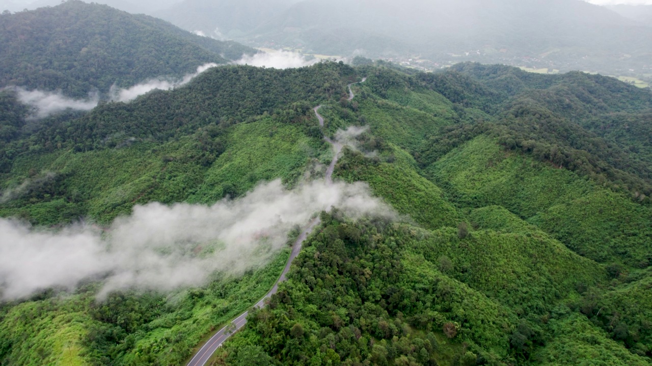 乡村道路穿过绿林和山峦的俯视图视频素材