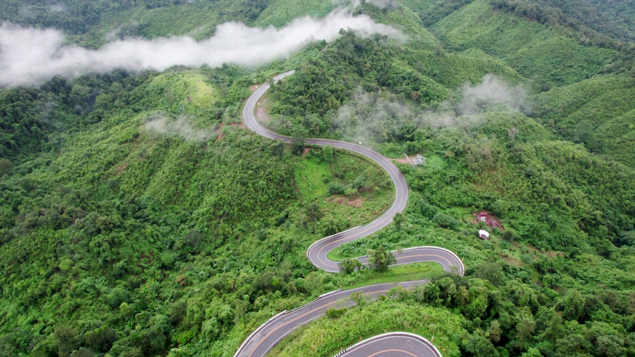 乡村道路穿过绿林和山峦的俯视图视频素材