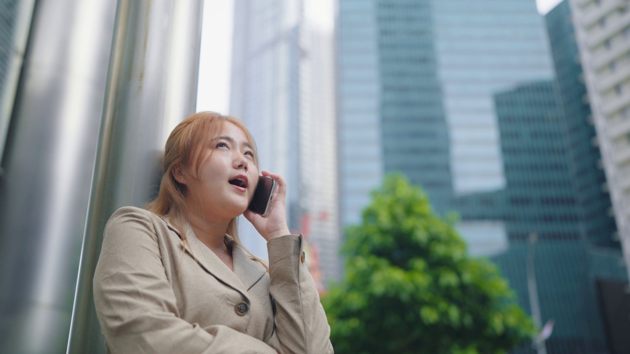 快乐的女商人微笑着穿着西装站在市中心的街道上打电话视频素材