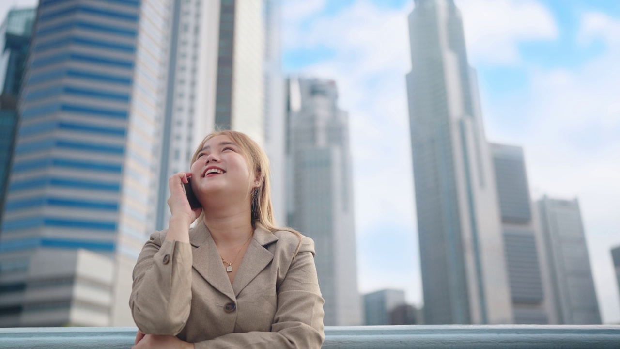 快乐的女商人微笑着穿着西装站在市中心的街道上打电话视频素材