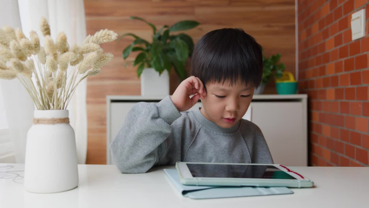 小男孩在餐桌上玩平板电脑视频素材