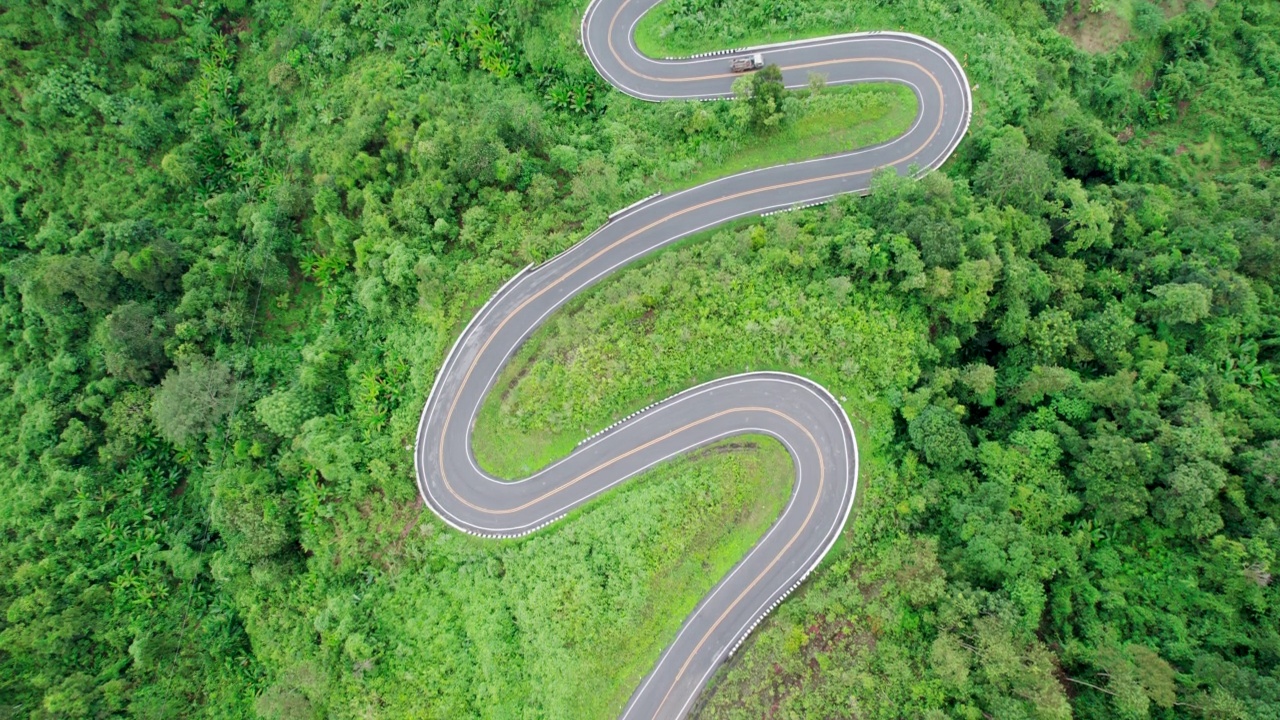 乡村道路穿过绿林和山峦的俯视图视频素材