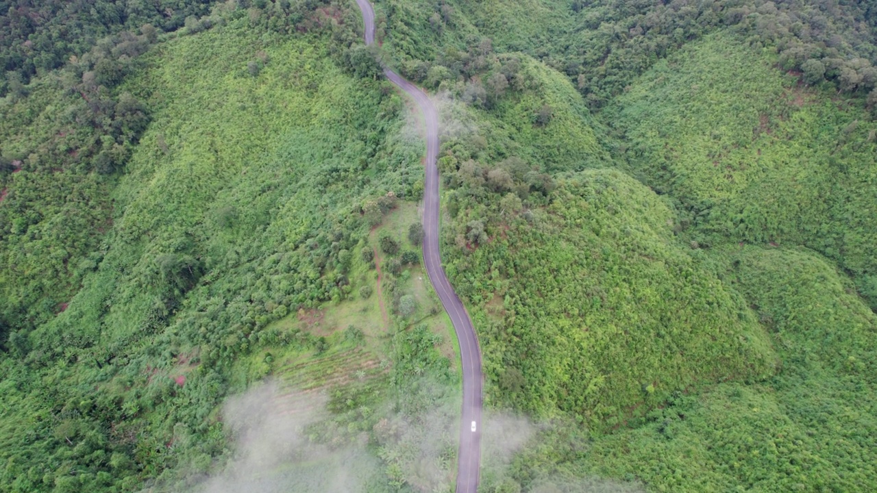 乡村道路穿过绿林和山峦的俯视图视频素材