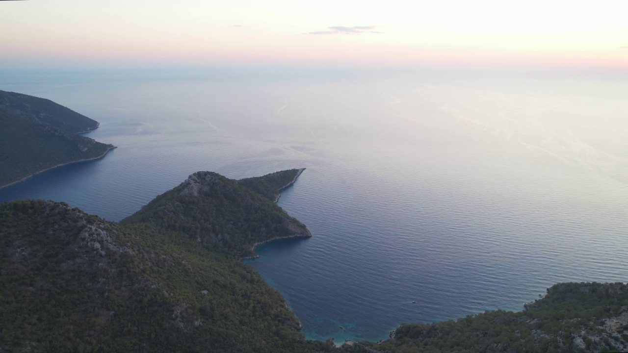 空中俯瞰海景绿色的岩石被蓝色的大海包围，无尽的大海在日落飞越山脉的天堂在地球上荒芜的泻湖视频素材