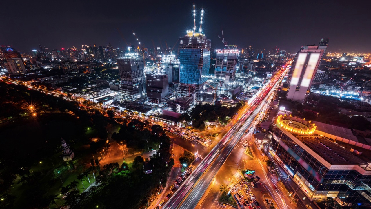 建筑工地夜间延时，亚洲城市道路上的汽车交通运输，高角视角。先进的建筑技术，繁忙的市中心城市景观，发展的工业国家理念视频素材