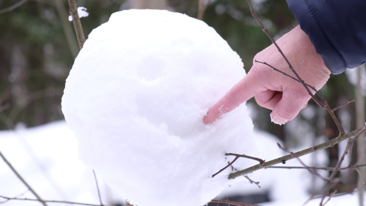 一个人在雪地上画了一张赞赏的脸，一个雪球粘在树上，在冬天的夜晚森林里有一张快乐的脸视频下载