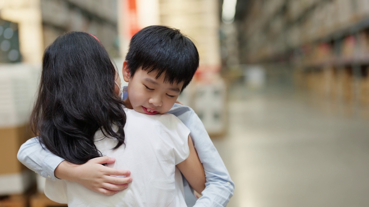 年轻的亚洲可爱男孩在商场购物时在仓库拥抱他的妈妈。母亲和儿童保育。孩子感到悲伤和失望。母亲鼓励儿子。家庭与爱情概念视频素材