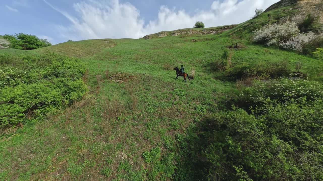 鸟瞰图高加索骑手在传统的穿着骑马在山区丘陵地形景观视频素材