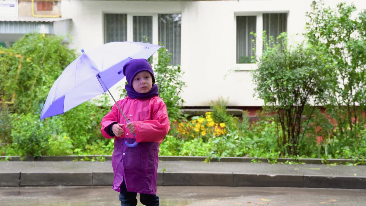 孩子在秋雨中玩耍。孩子用伞。户外乐趣的孩子，任何天气。防雨服，儿童用靴子和夹克视频素材