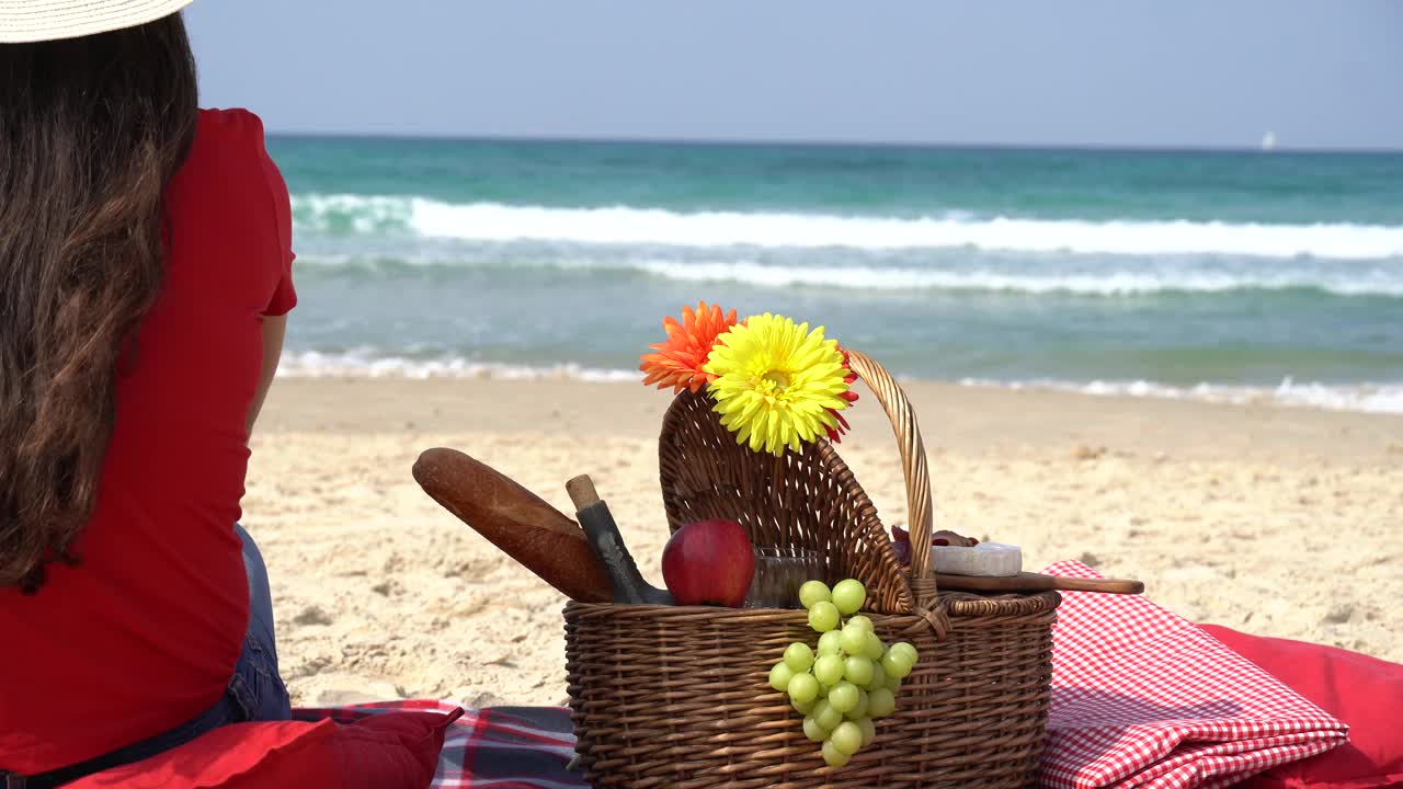 年轻的女孩在海滩上享受野餐。夏季休闲娱乐概念。沙滩上满是水果视频下载