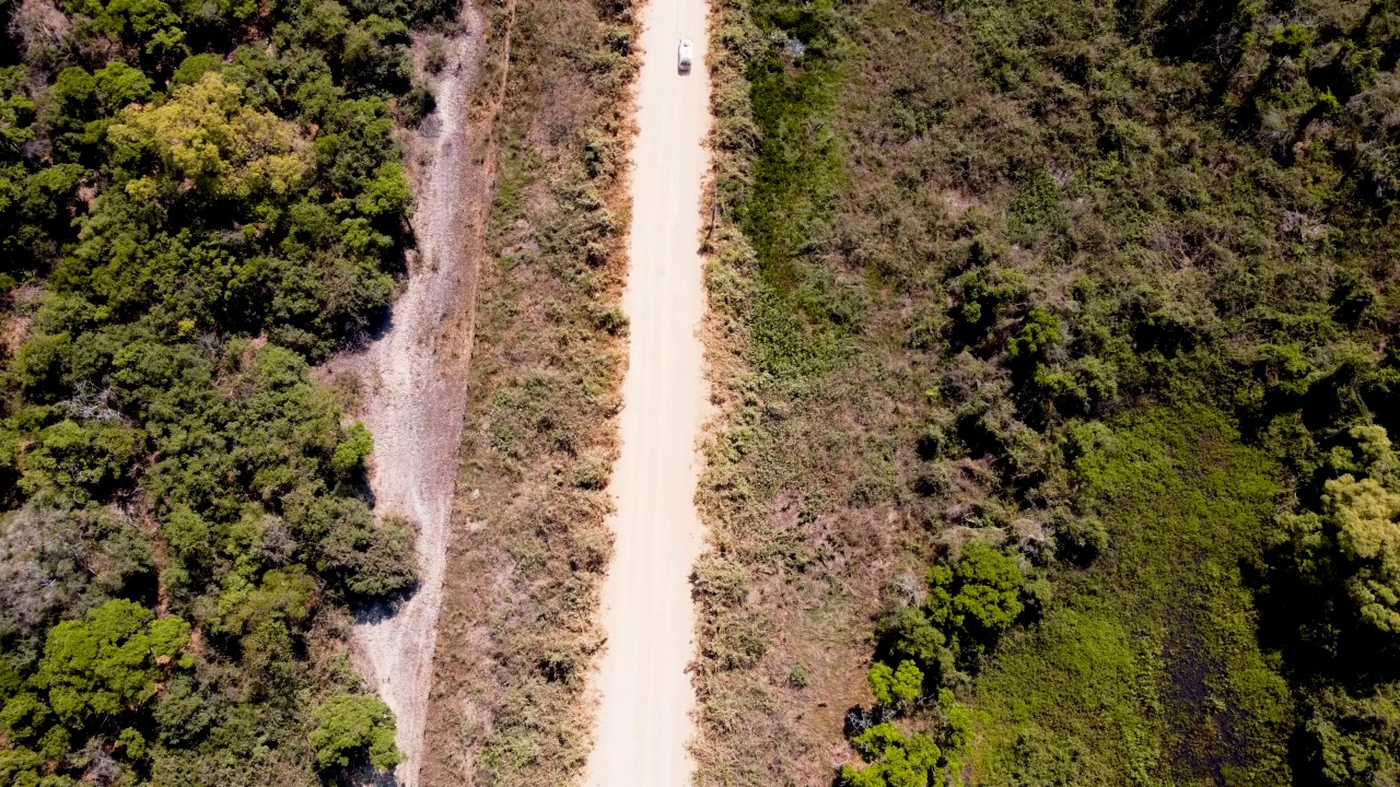 小型白色货车行驶在尘土飞扬的道路上，非常高的视角显示货车从下到上穿过屏幕视频素材