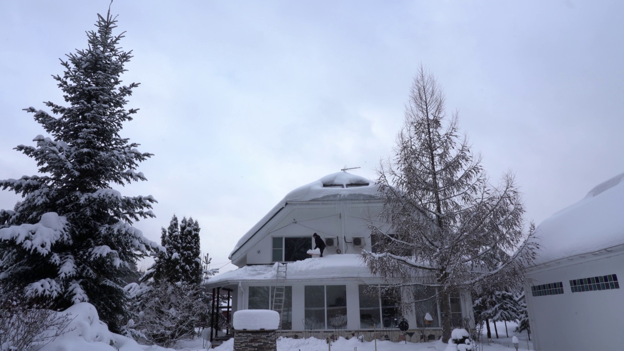 一位欧洲老人在一场大雪后正在清除屋顶上的积雪视频下载