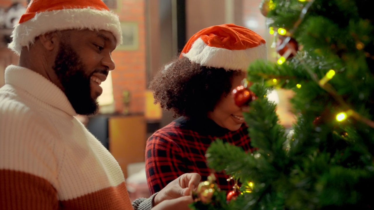 侧视图:一对快乐的中年黑人夫妇在客厅帮忙装饰圣诞树，等待他们的孩子和亲戚视频素材
