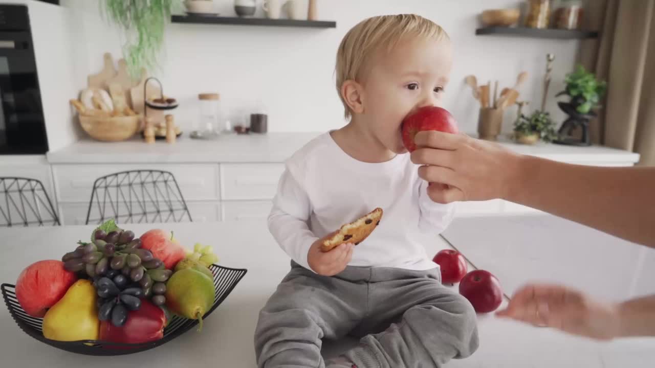 妈妈试图让孩子吃健康的食物，但孩子推开她的手，继续吃饼干视频素材