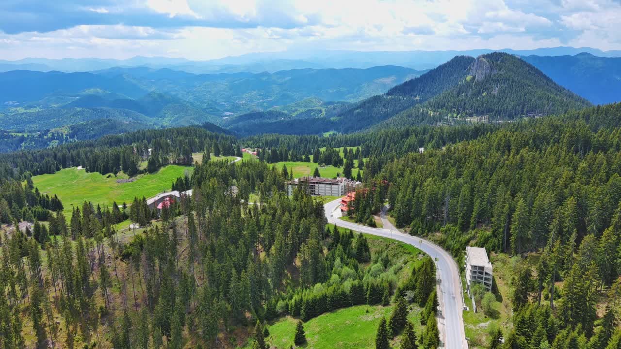 一条路经过布满云杉林和草地的小山，天空阴云密布视频素材