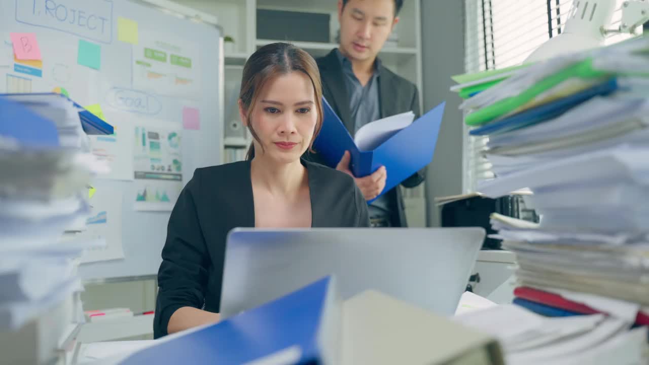 亚洲女商人听从商界领袖的指示。迷人美丽的女员工坐在桌子上，用笔记本电脑与她的老板经理在公司的工作场所。视频素材