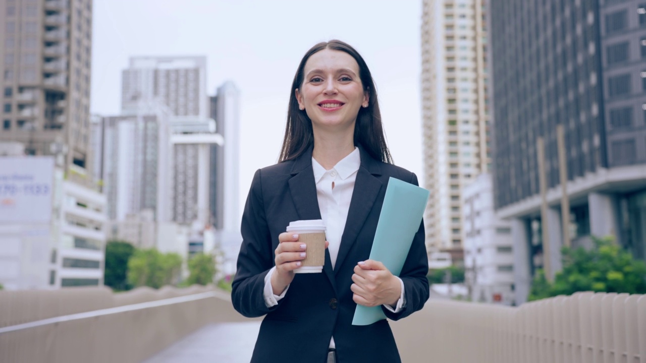 白种女商人拿着咖啡走在城市的户外。迷人美丽的女职员工人人们感到快乐和自信的同时花时间走到办公室的公司。视频素材