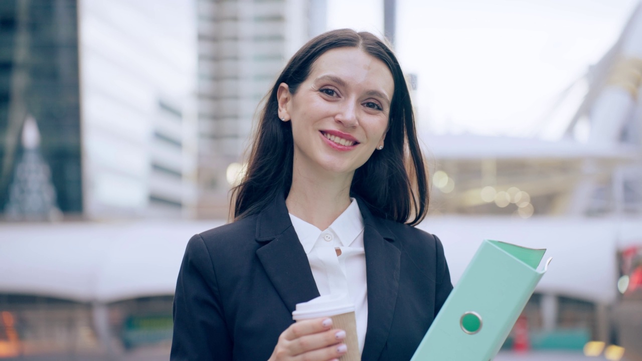 白种女商人拿着咖啡走在城市的户外。迷人美丽的女职员工人人们感到快乐和自信的同时花时间走到办公室的公司。视频素材