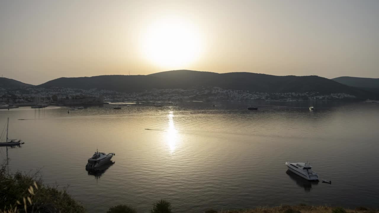 从山顶上的旧欧洲城市的夕阳与海港上的太阳的反射。平静的大海，日落的天空和太阳穿过云层。4 k的视频视频素材