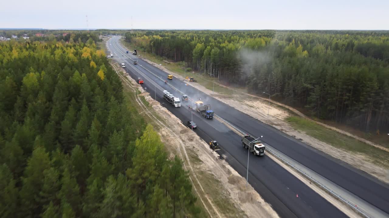 无人机俯瞰沥青摊铺机，道路工人和高速公路上的滚筒压路机视频素材