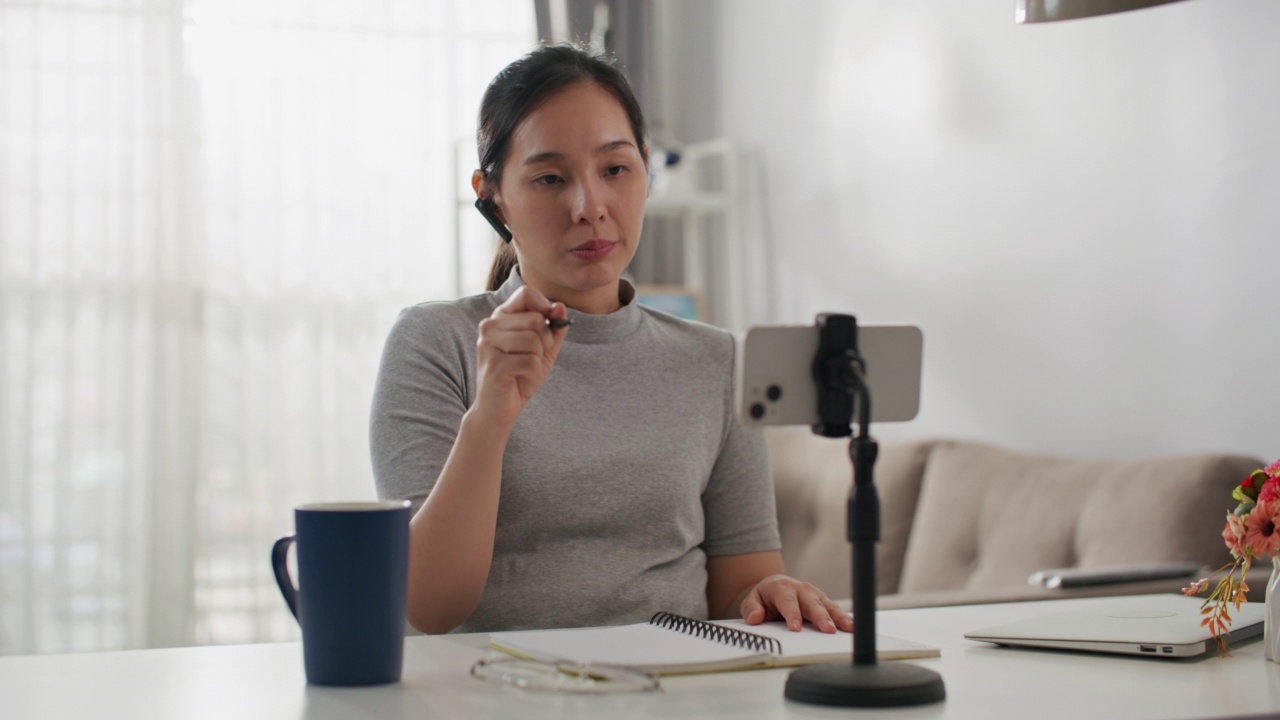 年轻的在线教练女人在智能手机上录制视频。视频素材