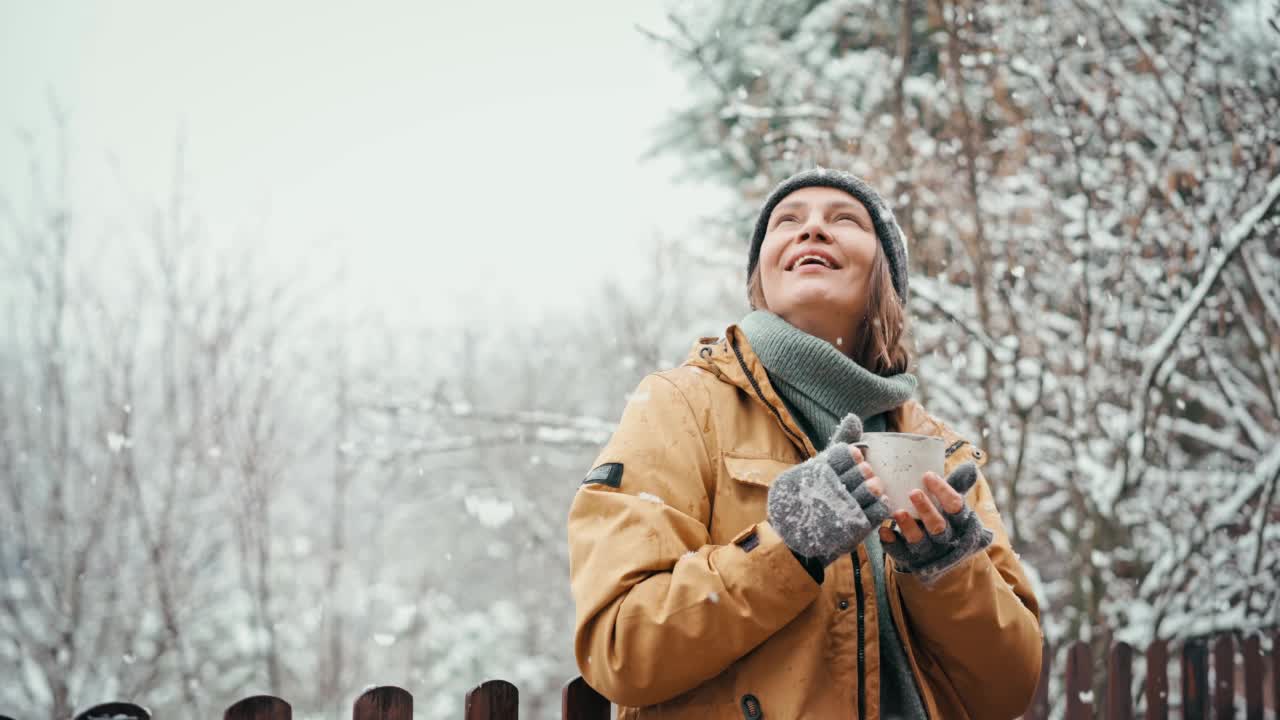 一位女士一边享受大雪，一边用杯子喝着热饮视频素材