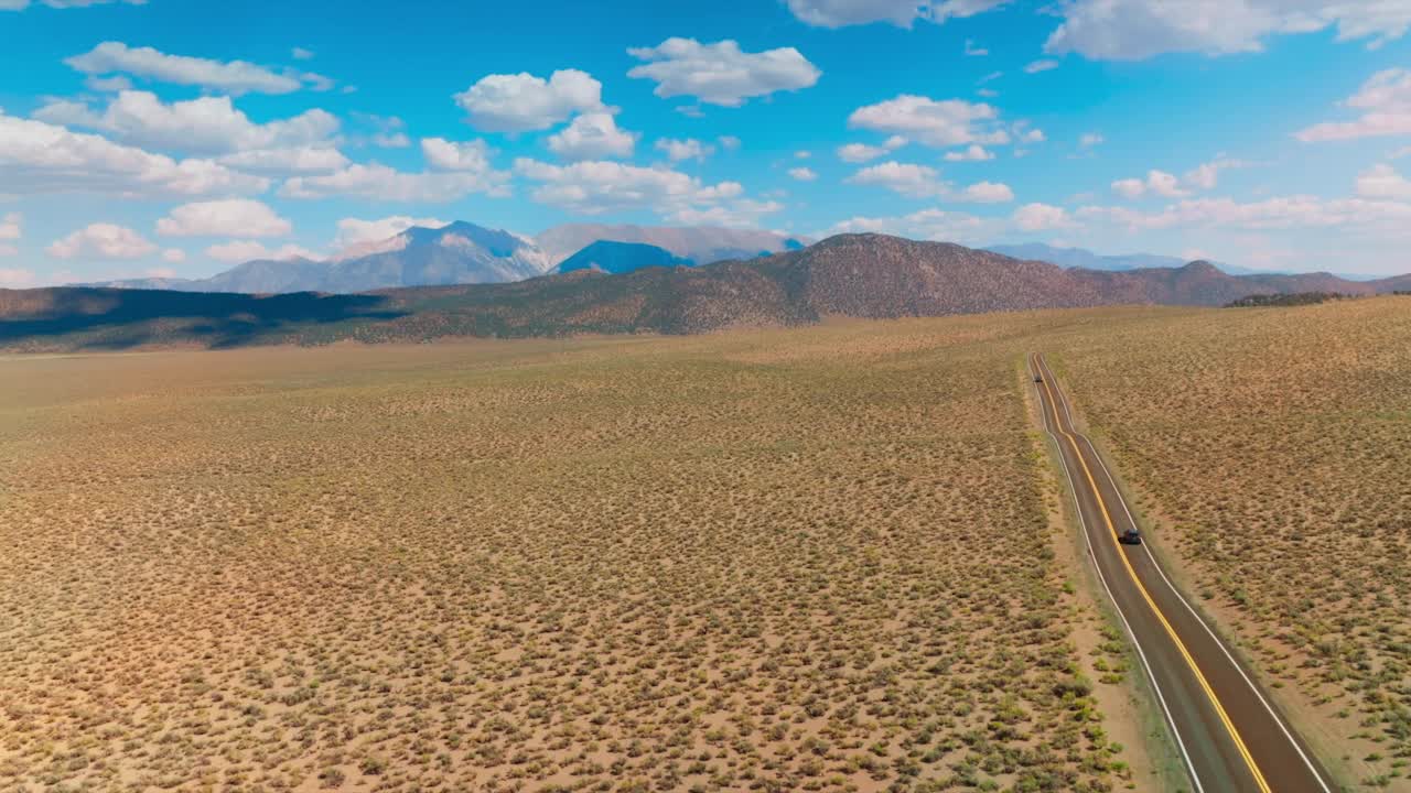 高速公路穿过沙漠通往美丽的内华达山脉。在炎热的晴天，令人惊叹的风景。鸟瞰图。视频素材