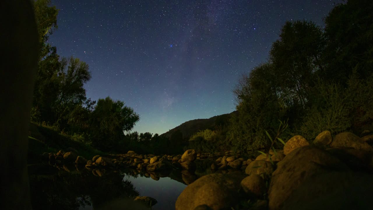 夜晚的天空，星星的轨迹在河流的时间流逝视频素材