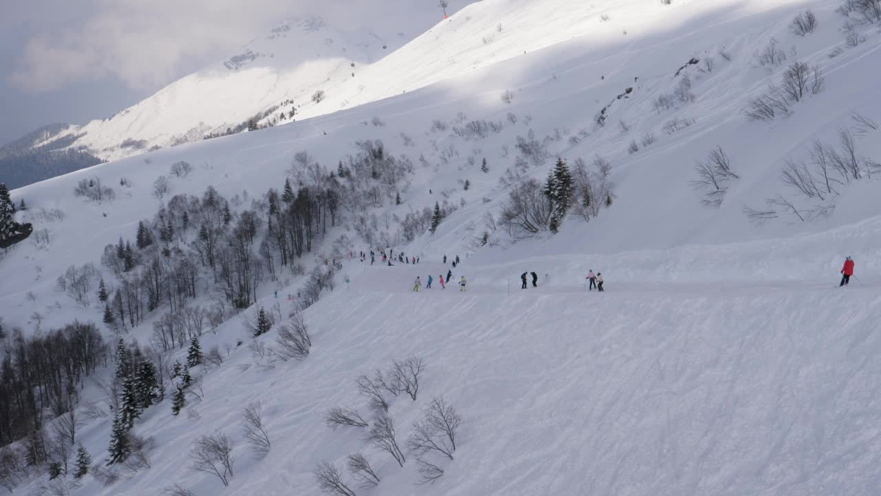 冬天，滑雪者和单板滑雪者在山上的雪坡上滑雪视频素材