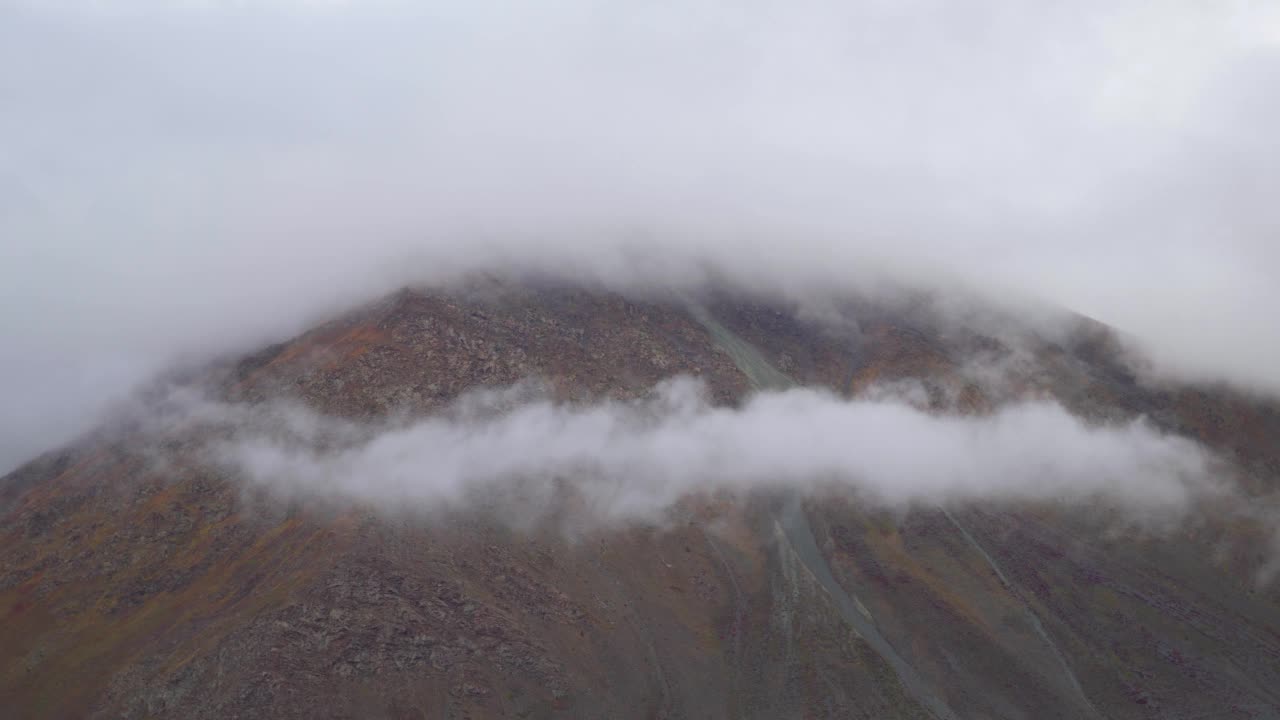 在印度喜马偕尔邦拉豪尔斯皮提地区的达尔恰，暴风雨天气中，云层在山下翻滚的4K镜头。在冬季风暴中，云在山下翻滚。视频素材