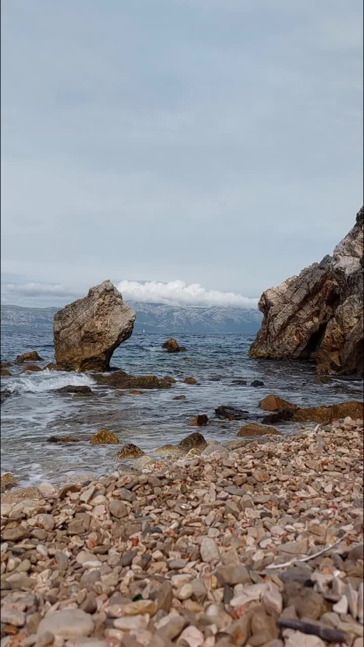 小海浪拍打着卵石滩上的岩石。海滩上的卵石。视频素材