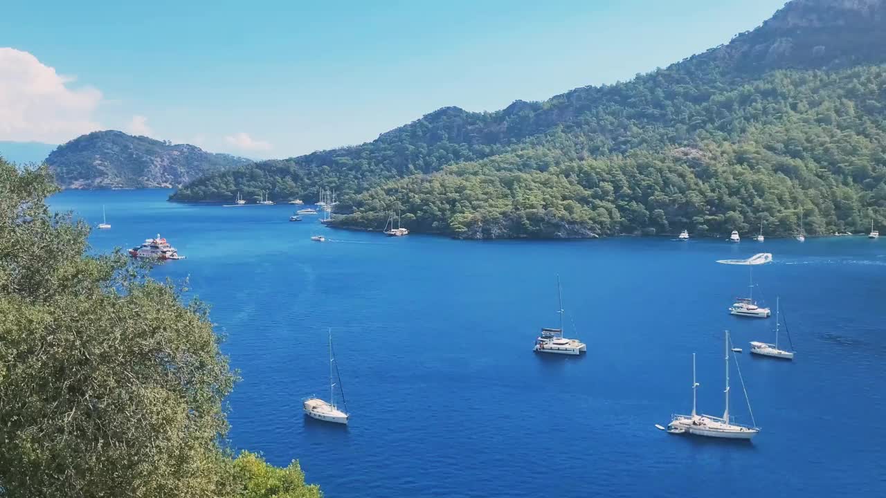 小船在一个美丽的蓝色海湾里，人们游泳，一个小小的海滩。(Sarsala。Dalaman。Mugla)视频素材