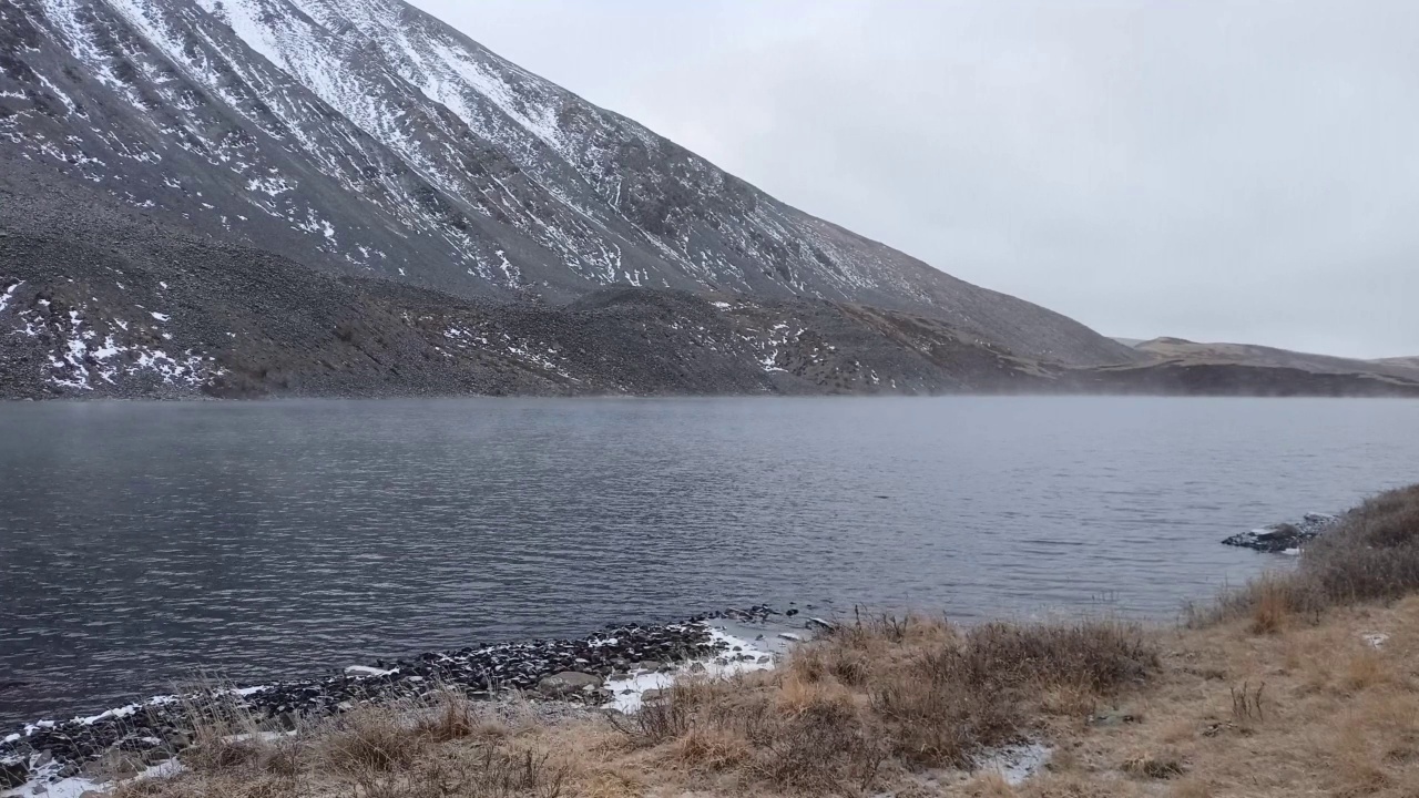 在初冬多云的雪天下，山上一个美丽的大湖的碎片。视频素材