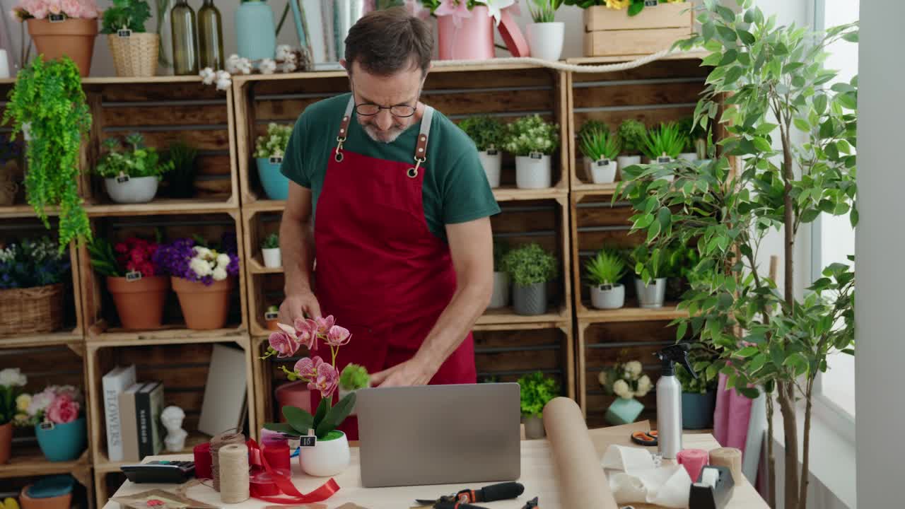 中年男子花店用笔记本电脑拿着花店的植物视频素材