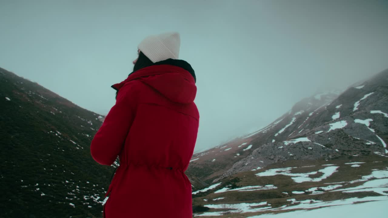 冬季登山旅行中，身穿红色夹克的女子用智能手机拍照视频素材