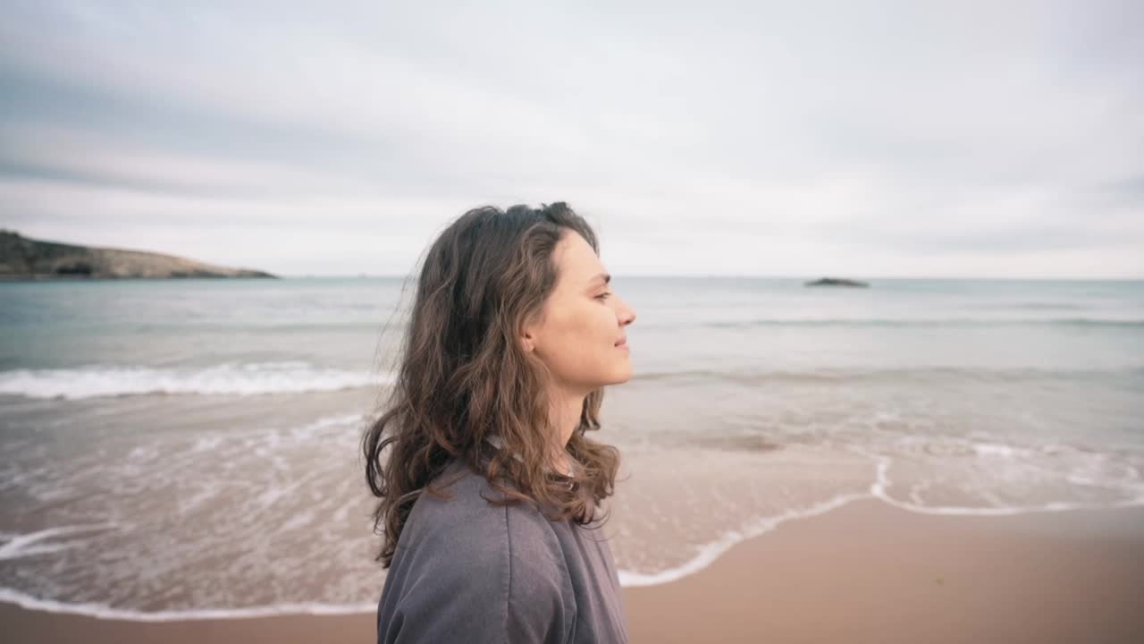 一位年轻的白人妇女站在海滩上享受新鲜空气视频素材