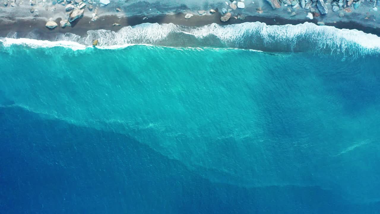 从空中俯瞰，蓝色的海浪拍打在海滩上。视频素材