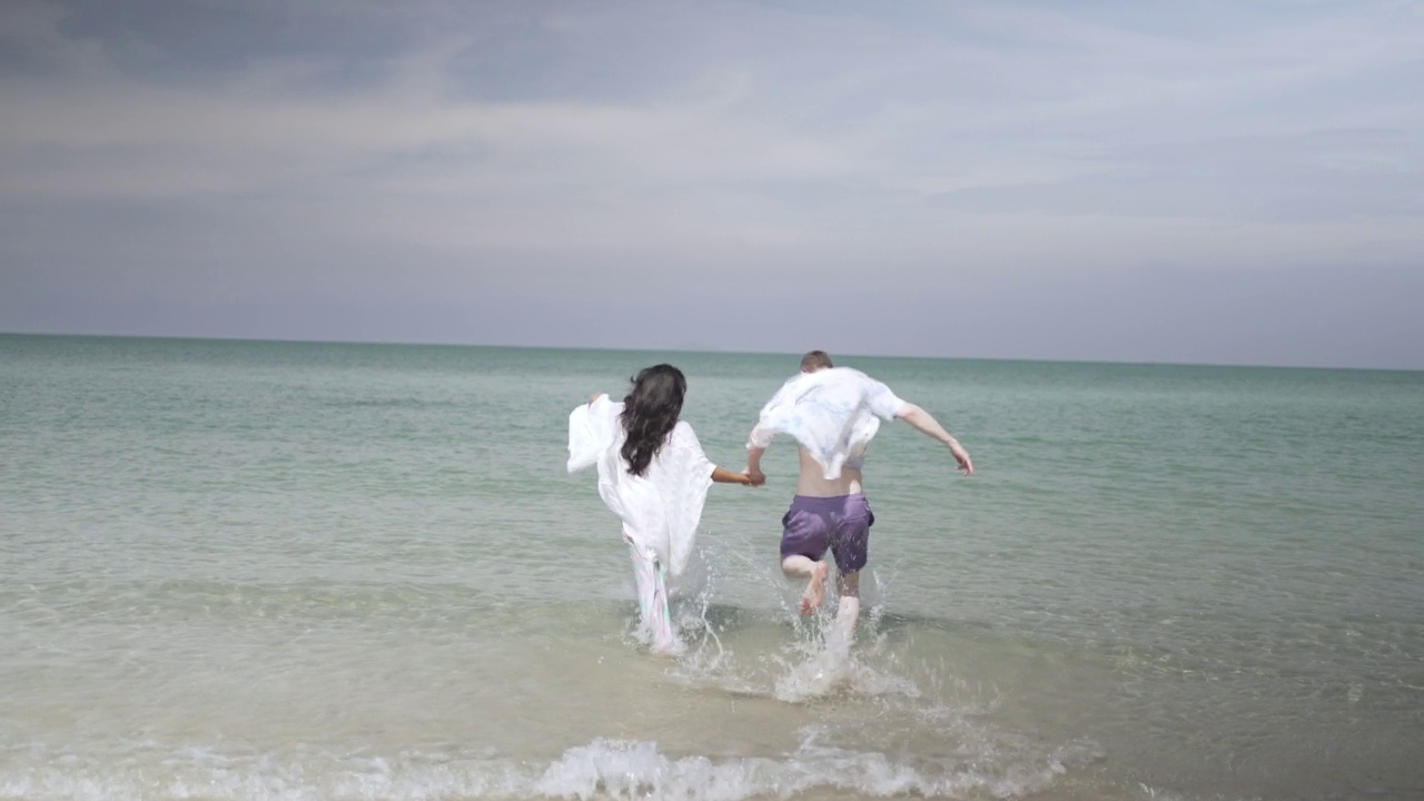 一对年轻夫妇在海滩上散步。视频素材