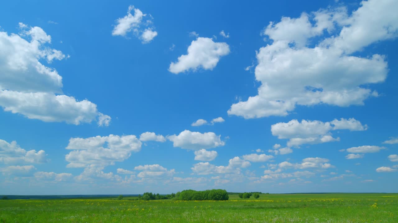 春天或夏天宽阔的风景与与云。蓝色多云的天空下生长着黄色蒲公英的乡村风景。广角镜头。间隔拍摄。视频素材