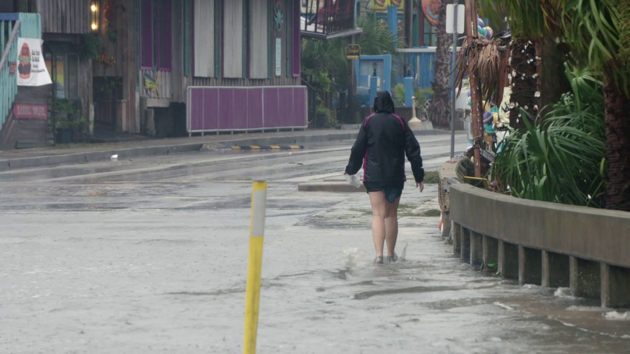 汹涌的河水、雨水、街道、行走的妇女、飓风“爱米娜”。视频素材