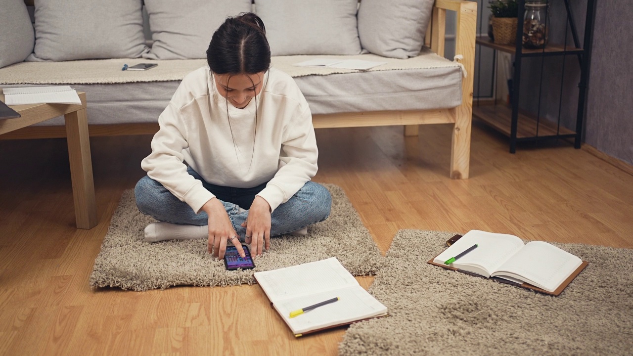 可爱的女性从学习中休息，坐在地板上玩游戏视频素材