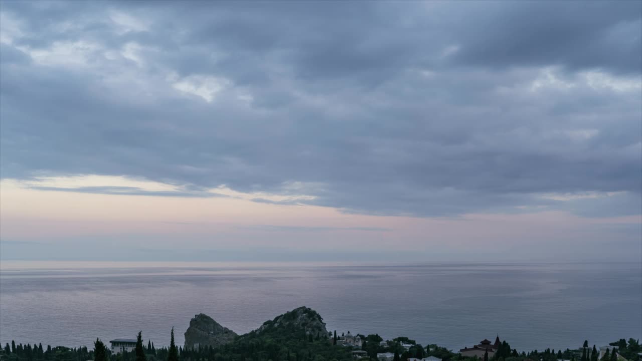 时间流逝。海边小镇的风景，海上有船只经过，日落时多云的天空呈现淡粉色、紫色和蓝色视频素材