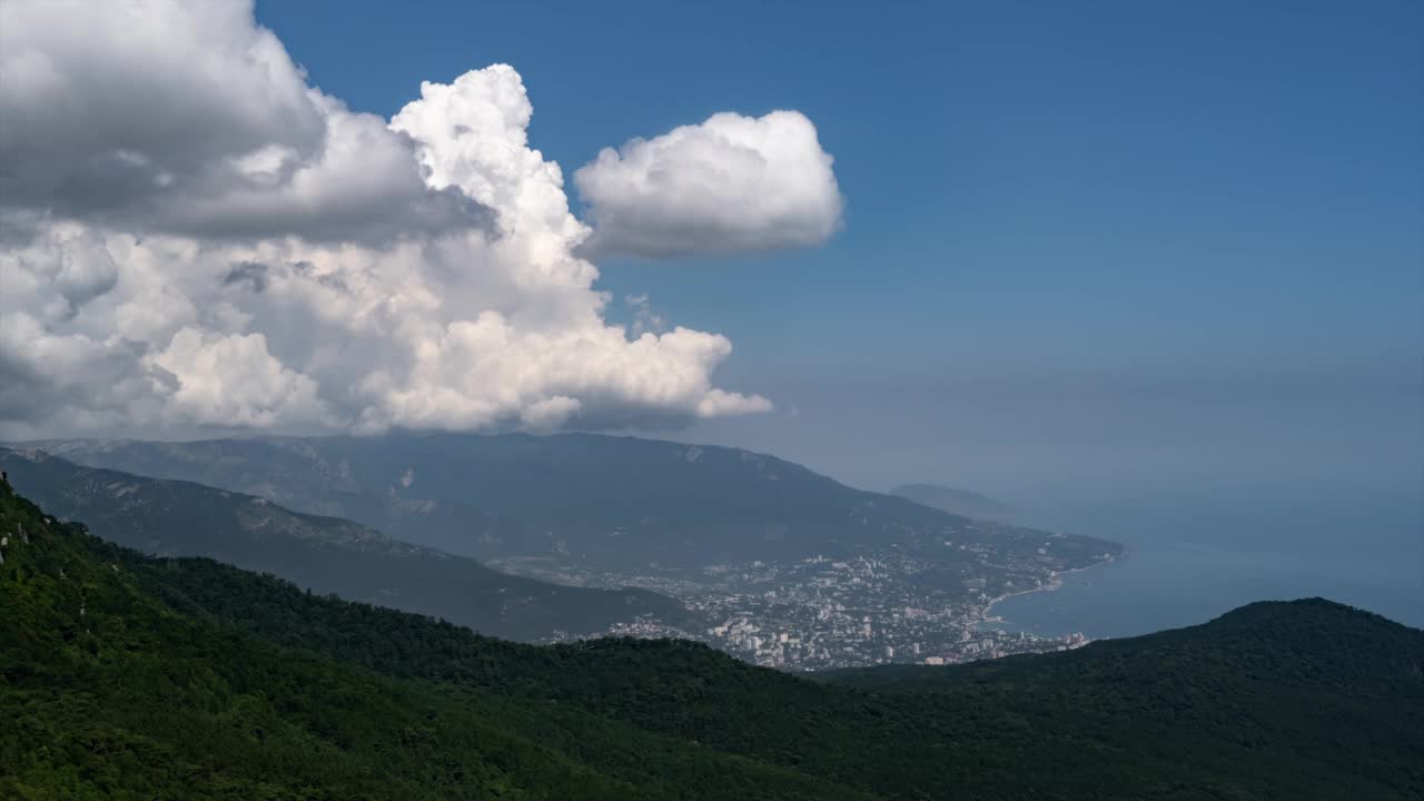 时间流逝。巨大的云在山、海和城市上空生长和移动。俯视图视频素材