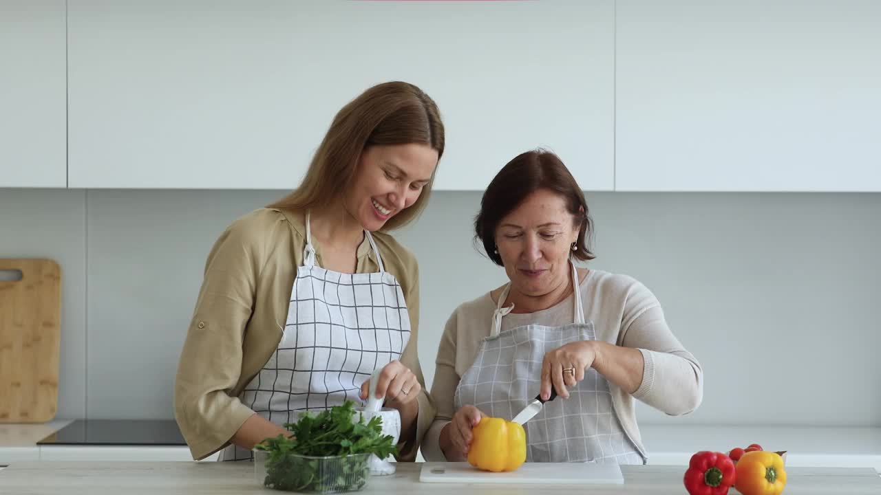 成年的女儿和年长的母亲一起在现代厨房做饭视频素材